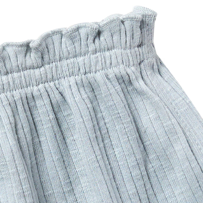Close-up of light blue textured fabric with an elastic waistband on a white background