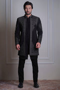 Model wearing a black embroidered sherwani with matching black trousers and formal shoes by Arsalan Iqbal