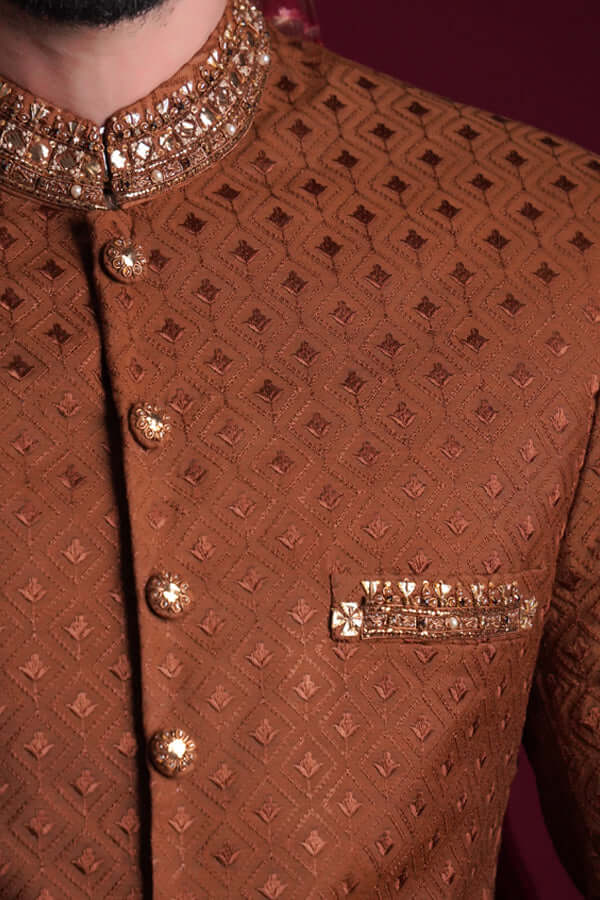 Macro detail of Arsalan Iqbal copper-brown sherwani featuring a gold-studded mandarin collar, embellished buttons, and a matching embroidered pocket welt.