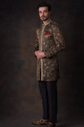 Side-profile view of Arsalan Iqbal luxury bronze-olive sherwani with gold ivy vine embroidery, featuring a gold leaf patterned placket, a red pocket square, and embellished loafers.