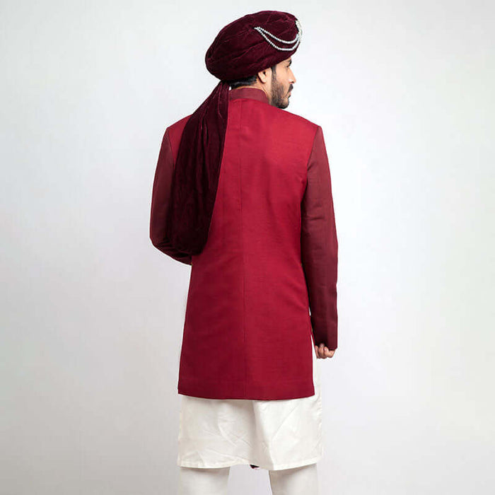 Back view of an Arsalan Iqbal teal paisley jamawar sherwani highlighting the drape of a white brocade shawl and the tailored fit.