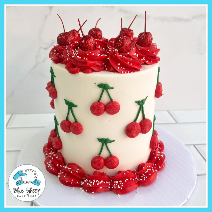 Cherry-themed birthday cake with hand-piped cherries, red buttercream swirls, edible glitter cherries, and white pearl sprinkles.