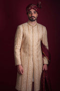 Arsalan Iqbal luxury cream and gold sherwani featuring vertical chevron embroidery and floral panels, paired with a maroon embroidered turban and shawl.