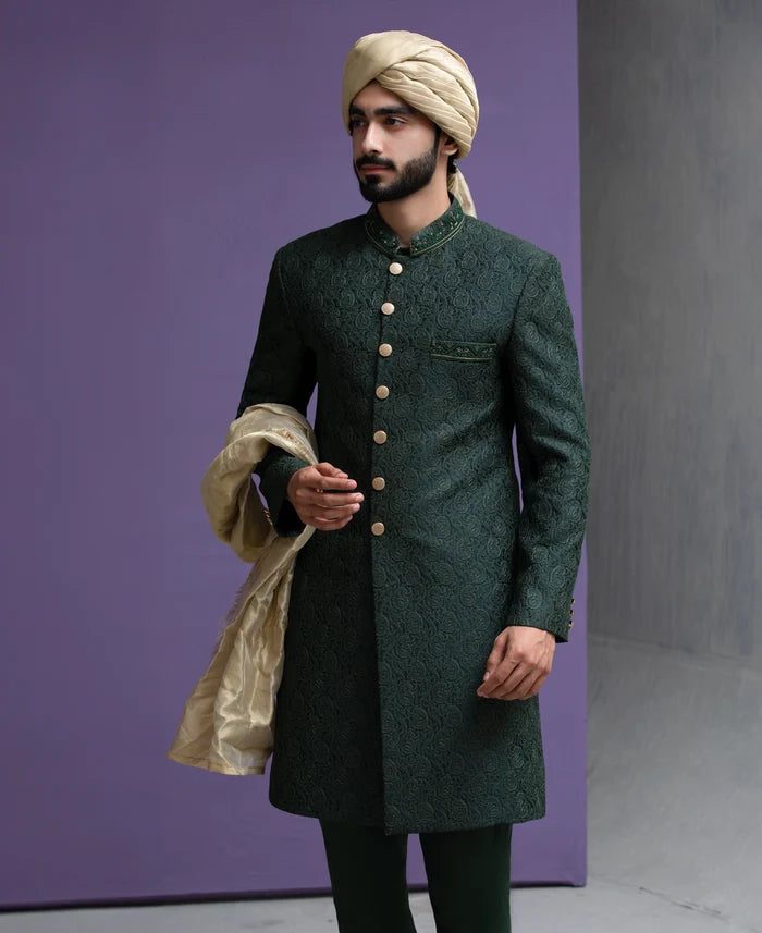 Close up shot of Arsalan Iqbal designer green sherwani featuring intricate embroidery, gold buttons, and a premium beige turban.