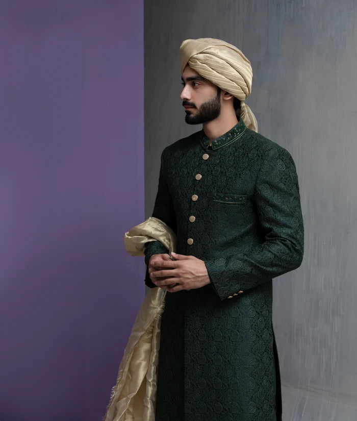 Arsalan Iqbal forest green designer sherwani with matching trousers, gold shawl, and traditional beige turban in a full-length shot.