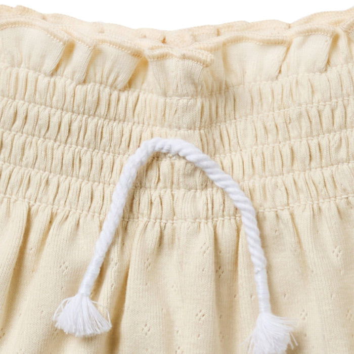 Close-up of beige fabric with a white tassel on a beige background