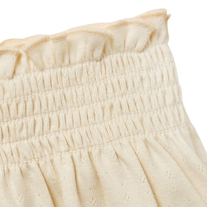 Close-up of a cream-colored fabric with ruffled texture on a white background