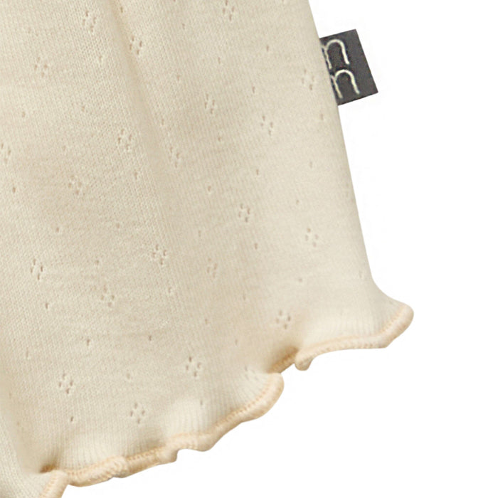 Close-up of a textured beige pillow with a brand tag on a white background