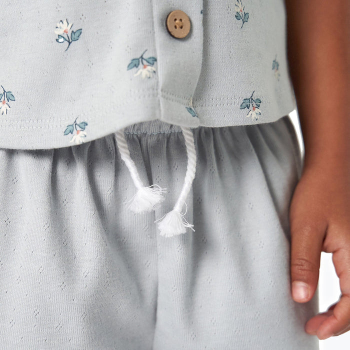 Light gray dress with floral embroidery and a button detail, worn by a child.