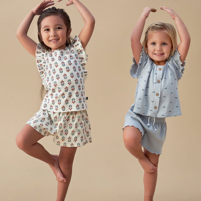 Two children wearing patterned outfits on a beige background