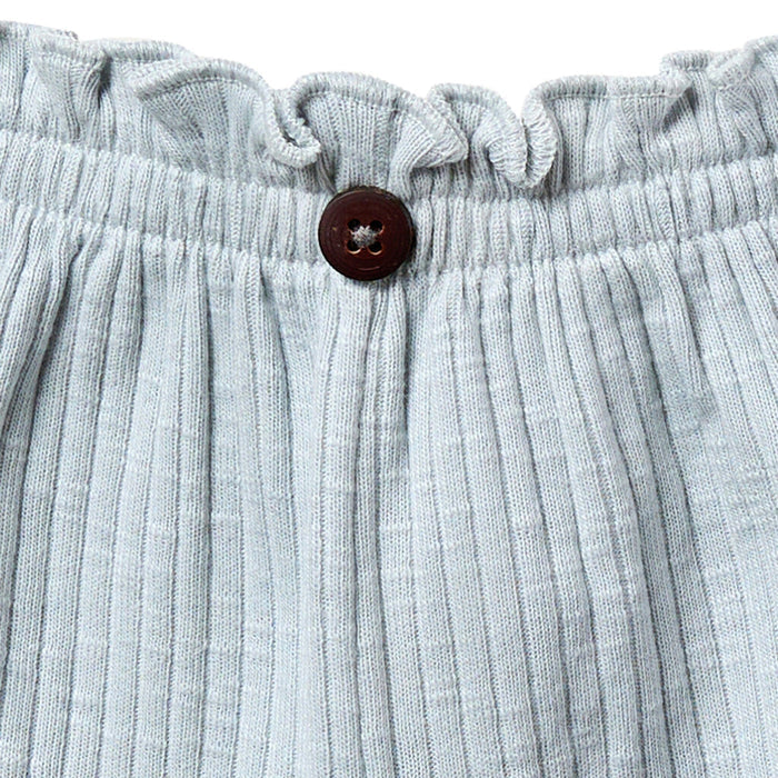 Close-up of light blue ribbed fabric with a button on a white background