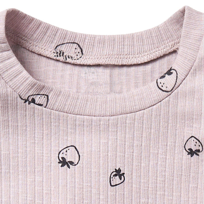 Close-up of a light pink fabric with black strawberry prints on a white background