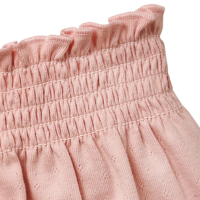Close-up of a pink textured fabric with ruffled top edge on a white background