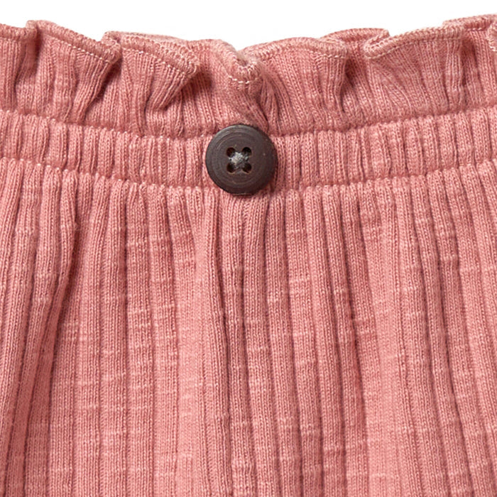 Close-up of pink textured fabric with a button on a matching background
