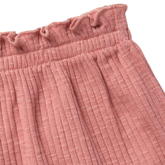 Close-up of a pink textured fabric with ruffled edge on a white background