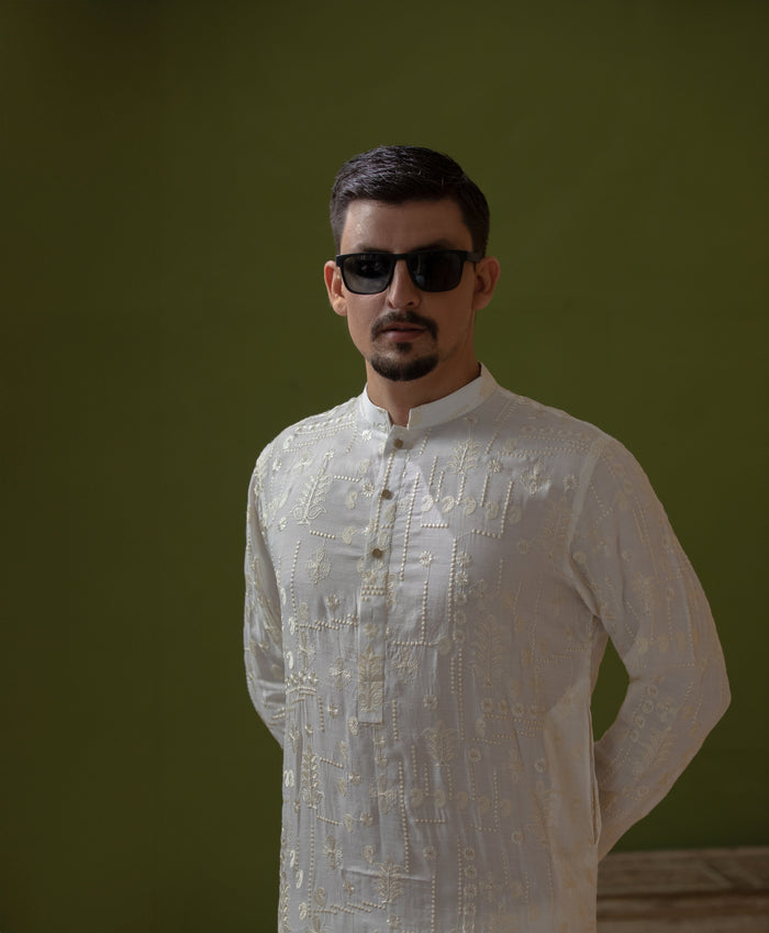 Man wearing Arsalan Iqbal's Off-White Ivory Kurta with allover silver and gold sequin embroidery, styled with black sunglasses against a deep green background