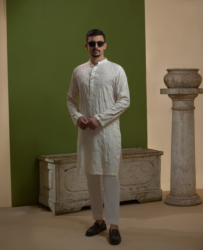 Man wearing Arsalan Iqbal's Off-White Ivory Kurta with allover silver and gold sequin embroidery, styled with black sunglasses against a deep green background