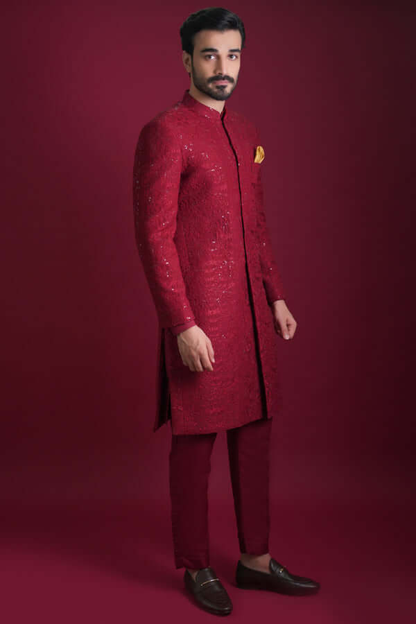 Side profile full view of Arsalan Iqbal luxury crimson red sherwani with tonal floral embroidery and silver sequins, paired with matching red trousers and a mustard silk pocket square.