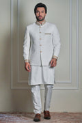 Men’s ivory jacquard prince coat with gold detailing, styled with matching kurta and churidar, formal wedding wear look.