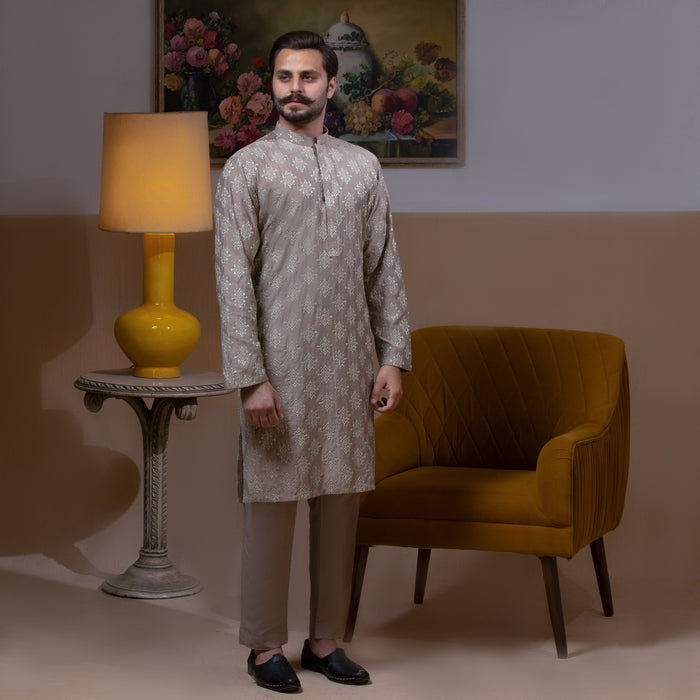 Arsalan Iqbal Beige Classic Chikankari Kurta Pyjama man wearing a beige full-sleeve kurta with intricate white chikankari floral embroidery, mandarin collar, and a relaxed tailored fit, styled in a warm indoor setting