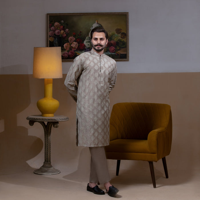 Arsalan Iqbal Beige Classic Chikankari Kurta Pyjama man wearing a beige full-sleeve kurta with intricate white chikankari floral embroidery, mandarin collar, and a relaxed tailored fit, styled in a warm indoor setting