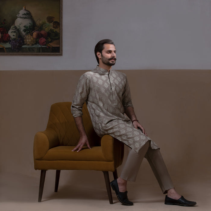 Arsalan Iqbal Beige Classic Chikankari Kurta Pyjama man wearing a beige full-sleeve kurta with intricate white chikankari floral embroidery, mandarin collar, and a relaxed tailored fit, styled in a warm indoor setting