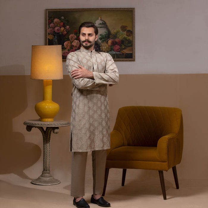 Arsalan Iqbal Beige Classic Chikankari Kurta Pyjama  man wearing a beige full-sleeve kurta with intricate white chikankari floral embroidery, mandarin collar, and a relaxed tailored fit, styled in a warm indoor setting