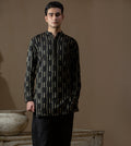 Man wearing Arsalan Iqbal's Black Kurta with allover gold metallic embroidery, styled with sunglasses and a silver watch against a dark background
