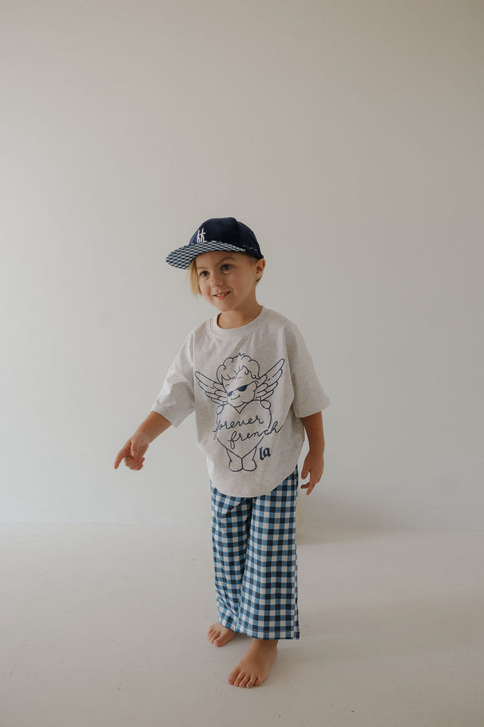 A young child models the forever french baby T-Shirt & Pant Set | ff Los Angeles, standing barefoot against a plain light background, smiling and pointing.