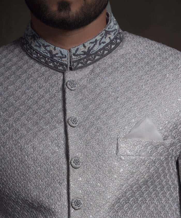 Close-up of Arsalan Iqbal mint green sherwani with silver geometric embroidery, featuring a charcoal grey mandarin collar with intricate silver threadwork and matching embroidered fabric buttons.