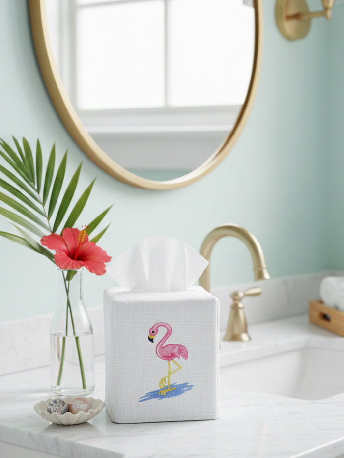 Tissue box with flamingo design on a bathroom counter, featuring a mirror and sink in the background.