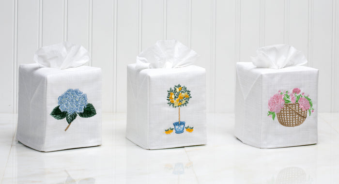 Three white gift boxes with floral designs on a wooden surface